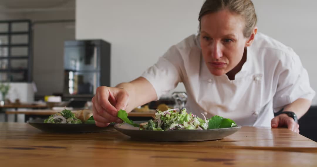 Image of chef finishing garnishing a plate.